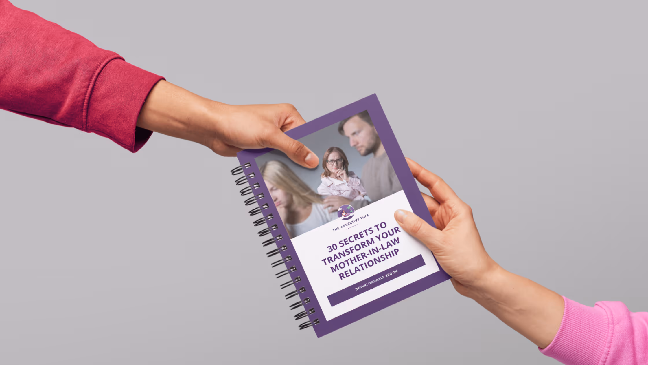 Two hands exchanging a spiral-bound booklet titled '30 Secrets to Transform Your Mother-in-Law Relationship' with a purple border and images of three people on the cover.